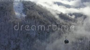 滑雪电梯在低地白色雪山云林上移动。 提供带滑雪者和滑雪板的滑雪缆车